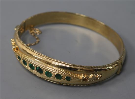 An Edwardian style 9ct gold and emerald hinged bangle.